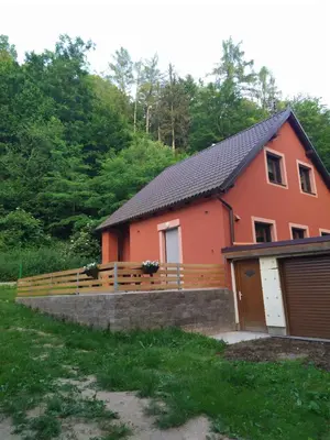 a orange house with a fence and a garage at Chata na řece Sázavě in Samopše