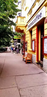 a bench in front of a store with a building at Cozy studio in Vinohrady in Prague