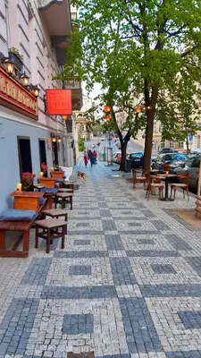 a sidewalk with tables and benches on a city street at Cozy studio in Vinohrady in Prague