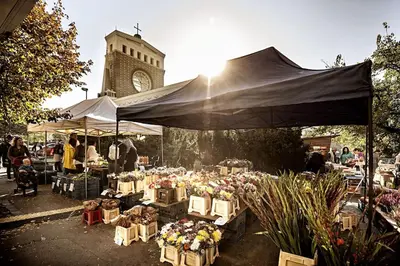 an outdoor market with flowers on tables in front of a tower at Cozy studio in Vinohrady in Prague