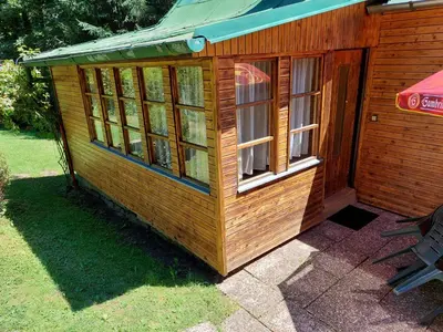 a wooden cabin with windows on the grass at ZÁTOKA Živohošť - Apartmány in Chotilsko