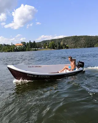 a man sitting on a boat in the water at ZÁTOKA Živohošť - Apartmány in Chotilsko