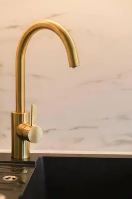 a kitchen sink with a gold faucet on a counter at Charming apartment for two in uptown in Prague