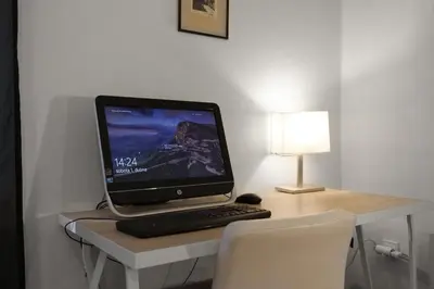 a computer monitor on a desk with a keyboard and a lamp at LIKE AT HOME IN CENTER OF PRAGUE in Prague