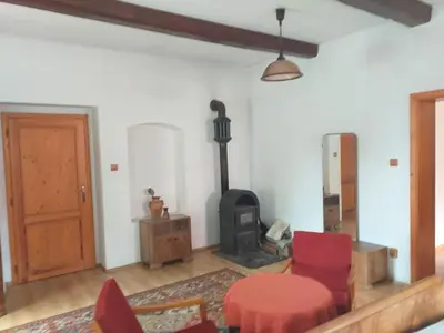a living room with a wood stove and red chairs at Apartmán Chrpa in Snědovice