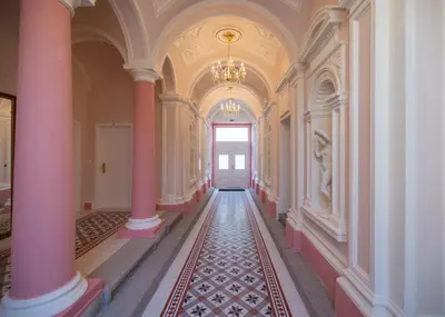 an empty hallway with pink columns and a chandelier at NaNa Flat in Prague