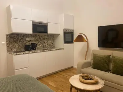 a living room with a kitchen with a couch and a table at NaNa Flat in Prague