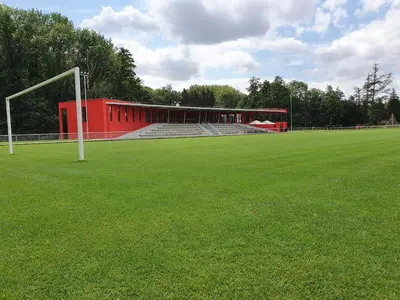 a soccer field with a red building and a goal at Penzion na hřišti in Radím