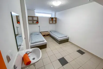 a bathroom with two beds and a sink and a mirror at Penzion Pomeranč in Louny