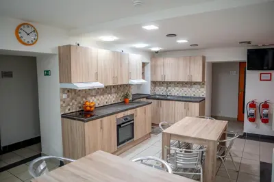 a kitchen with wooden cabinets and tables and a clock at Penzion Pomeranč in Louny