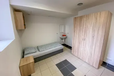 a small bedroom with a bed and a cabinet at Penzion Pomeranč in Louny