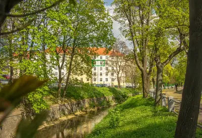 a river in a park with trees and a building at Double King Size Sunny Suite In Castle Area in Prague