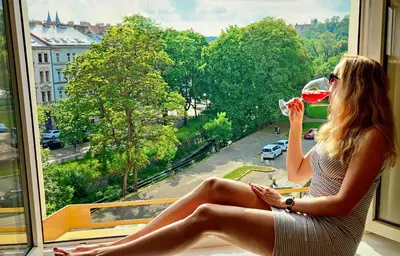 a woman sitting in a window drinking a glass of wine at Double King Size Sunny Suite In Castle Area in Prague