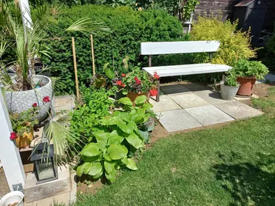 a white bench in a garden with flowers and plants at Paradise villa apartment in Prague