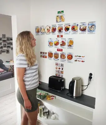 a woman standing in front of a counter with food on the wall at King Size Sunny Home 19 minutes to Center in Prague