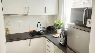 a kitchen with white cabinets and a sink and a microwave at King Size Sunny Home 19 minutes to Center in Prague