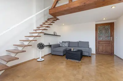 a living room with a staircase and a couch at Bright and Spacious Attic Apartment in Prague