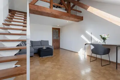 a living room with a couch and a staircase at Bright and Spacious Attic Apartment in Prague