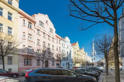 a row of parked cars on a street with buildings at Bright and Spacious Attic Apartment in Prague