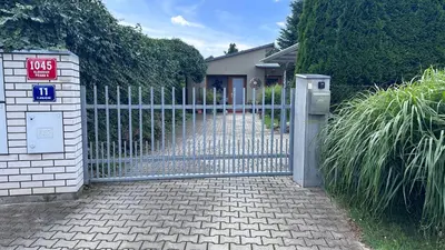 a gate in a driveway with a house at Luxusní apartmán v Praze Klánovicích na zahradě, 20 minut do centra Prahy in Šestajovice