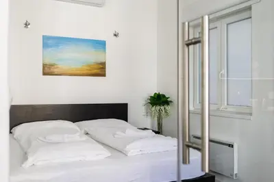a white bedroom with a bed with white pillows at Prague Days - Open-plan Studio with AC near National Theatre in Prague