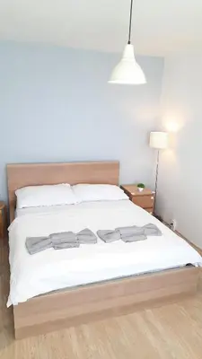 a bedroom with a bed with white sheets and a lamp at Apartment Kamýk in Prague