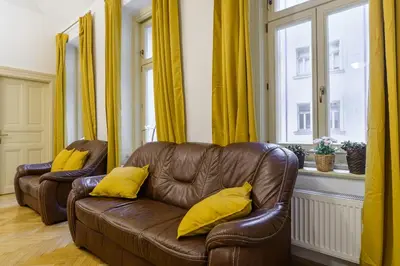 a living room with a brown leather couch with yellow pillows at Superb apartments near Dlouha street in Prague