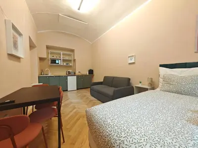 a bedroom with a bed and a couch and a kitchen at Spacious, Light Studio Apartment in Vinohrady in Prague
