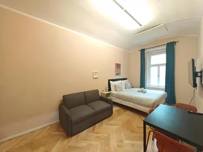 a bedroom with a couch and a bed and a window at Spacious, Light Studio Apartment in Vinohrady in Prague