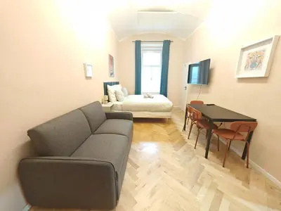 a living room with a couch and a table and a bed at Spacious, Light Studio Apartment in Vinohrady in Prague
