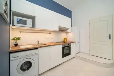 a kitchen with white cabinets and a washer and dryer at Cosy, retro-styled flat in beautiful Zizkov in Prague