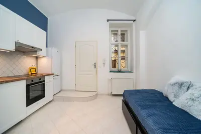 a bedroom with a bed and a kitchen with white cabinets at Cosy, retro-styled flat in beautiful Zizkov in Prague