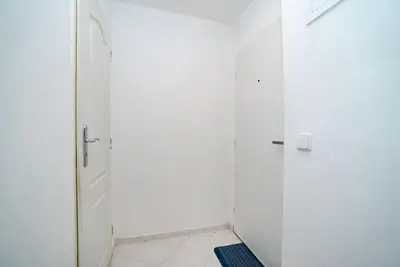 a white bathroom with a shower and a door at Cosy, retro-styled flat in beautiful Zizkov in Prague