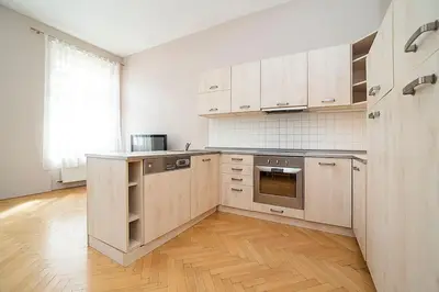 a kitchen with white cabinets and a wooden floor at Cozy and sunny apartment in uptown in Prague