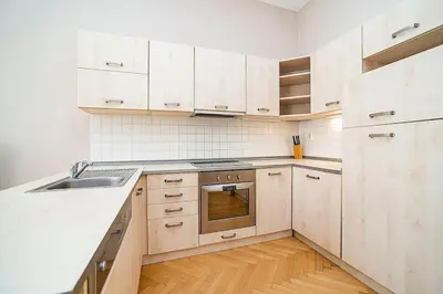 a kitchen with white cabinets and a sink and a stove at Cozy and sunny apartment in uptown in Prague