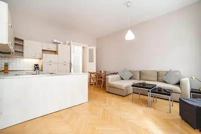 a white living room with a couch and a kitchen at Cozy and sunny apartment in uptown in Prague