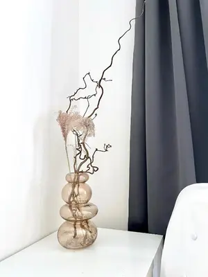 a vase with flowers on a white table at Jana's apartment, free parking in Prague