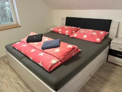 a bed with two red pillows on top of it at Apartmán Jenčice v Českém středohoří in Jenčice