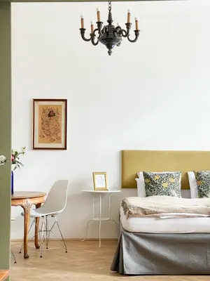 a bedroom with a bed and a table and a chandelier at TurnKey I Vintage Terrace Apartment in Prague