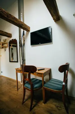 a desk with two chairs and a television on a wall at Antonio Residence in Škvorec