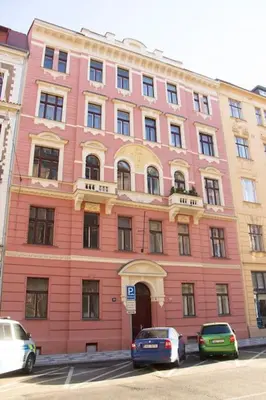 a pink building with cars parked in front of it at Balcony King Suite 12 min from Charles Bridge in Prague