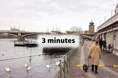 a woman walking a dog next to a river with a boat at Balcony King Suite 12 min from Charles Bridge in Prague