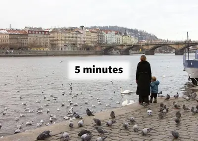 a woman and a child standing next to a flock of birds at Balcony King Suite 12 min from Charles Bridge in Prague