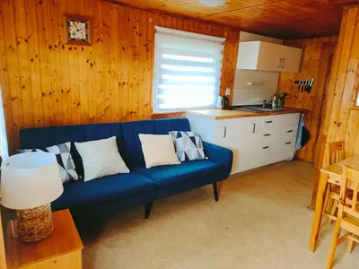a living room with a blue couch and a kitchen at Chata Slapy - Ždáň in Slapy