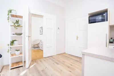a kitchen with white walls and wooden floors and white doors at Prague Days - Two-bedroom Apartment with Workspace right next to Old Town Square in Prague