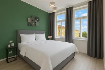 a bedroom with a white bed and two windows at Kinsky Garden Apartments and Suites by Dwellfort in Prague