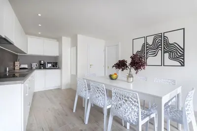 a white kitchen with a white table and chairs at Kinsky Garden Apartments and Suites by Dwellfort in Prague
