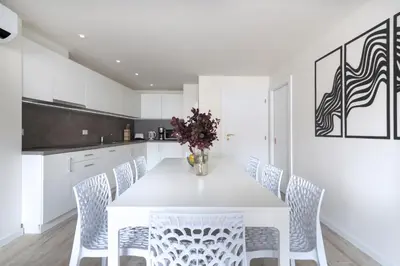 a white kitchen with a white table and chairs at Kinsky Garden Apartments and Suites by Dwellfort in Prague