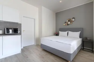 a bedroom with a white bed and a kitchen at Kinsky Garden Apartments and Suites by Dwellfort in Prague