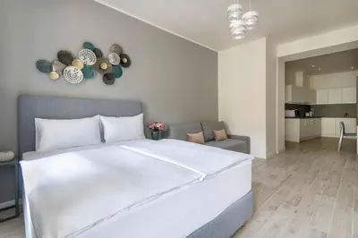 a bedroom with a large white bed and a living room at Kinsky Garden Apartments and Suites by Dwellfort in Prague